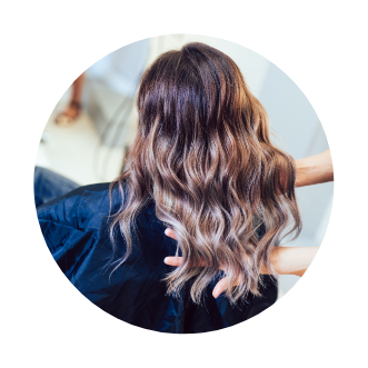 A woman with long wavy hair in a circular photo, promoting hair extensions