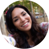 A woman with a big smile and hair extensions, and a tree in the background.